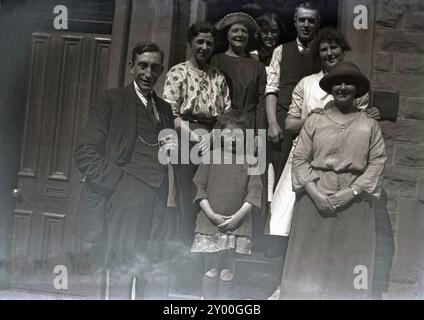 1930s, historical, a family picture outside a house, showing the clothes and fashions of the era. Two ladies are wearing hats and the gentleman at the front in a three-piece suit, with watch and chain or watch fob. Before the introduction of the wristwatch, most watches were designed to be carried in the pocket of a suit or jacket. Stock Photo