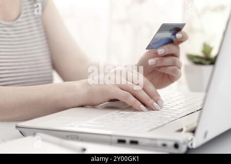 Close up of female hands using modern computer and credit card, high key. Shopping online Stock Photo