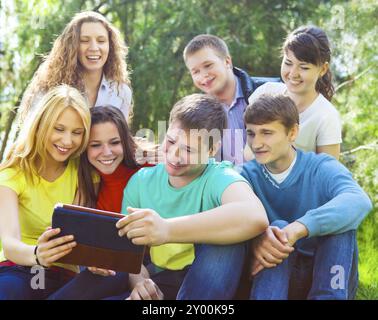Young college students using tablet computer while doing homework in the park Stock Photo