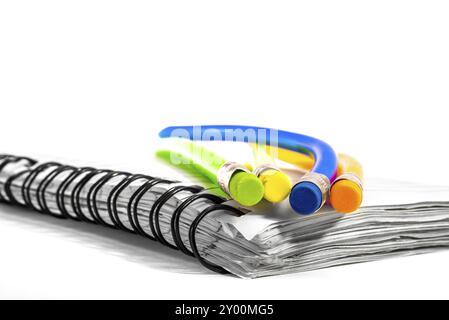 Colourful bend pencils together on a notebook Stock Photo