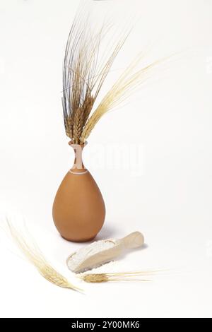 Earthenware vase with ears of wheat with wooden spoon with flour isolated on white background and copy space Stock Photo