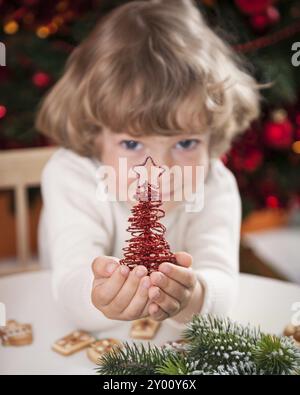 Happy child holding handmade decoration against Christmas lights Stock Photo