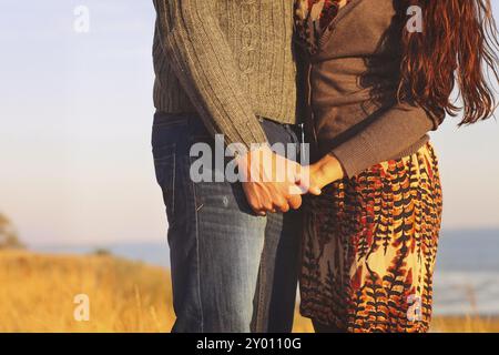Young couple in love walking by the sea holding hand at sunset time Stock Photo
