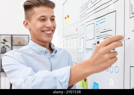 Developing UI design. Man drawing website wireframe on whiteboard indoors Stock Photo