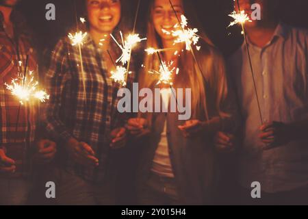 Young happpy people with sparklers having fun on outdoor party Stock Photo