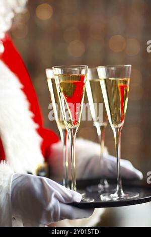 Santa Claus holding champagne glasses on the tray. Closeup Stock Photo