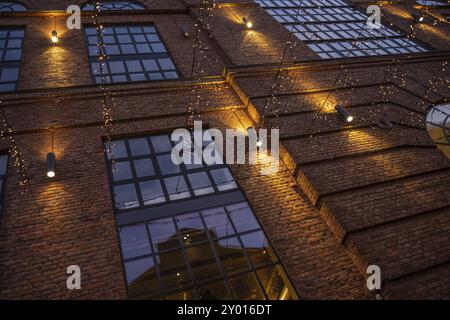 Christmas decoration lights hanging from the facade of a brick building Stock Photo