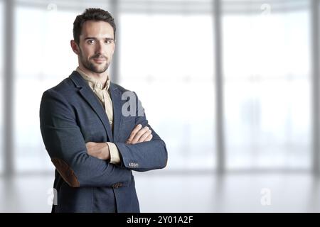 Casual business man with arms crossed with a bookshelf behind him Stock Photo