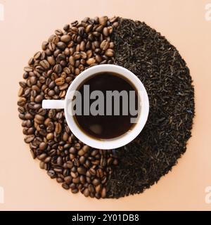 Beige flat lay background with white ceramic coffee cup, roasted coffee beans and dried tea leaves. Idea and composition, choice between coffee beans Stock Photo