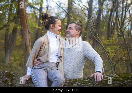 Beautiful couple sitting together on the tree in park hugging Stock Photo