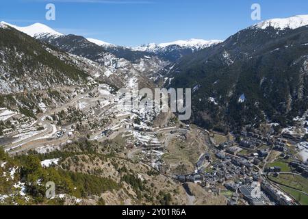 Verschneite Berge und ein Tal mit Strassen und verstreuten Gebaeuden unter einem klaren blauen Himmel in Andorra, Mirador del Roc del Quer, Blick auf Stock Photo