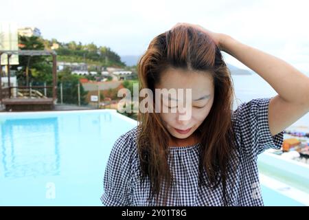 Dolsan-eup, Yeosu-si, South Korea - July 26, 2024: Young woman watching sunrise at a resort with a swimming pool overlooking the sea in Yeosu Stock Photo