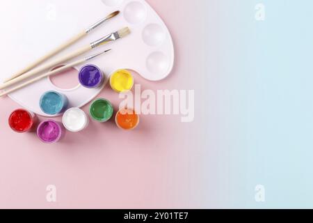 Colorful watercolor palette and brushes on gradient pink and blue background, copy space flatlay Stock Photo