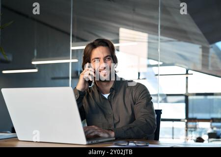 Happy business man worker talking on cellphone working on laptop in office. Stock Photo