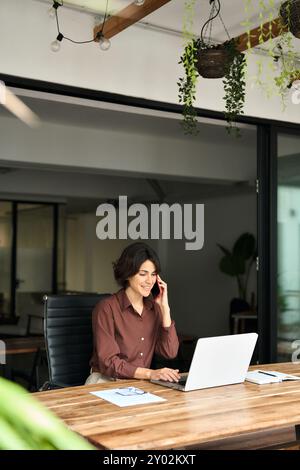 Busy young business woman talking on phone making call in office. Stock Photo