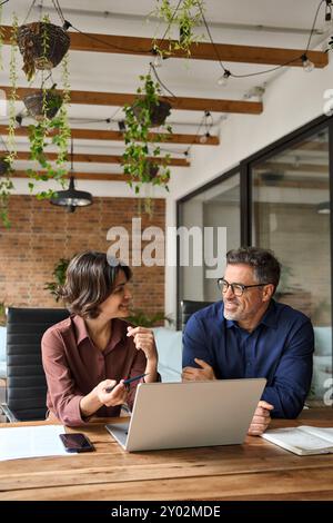 Two happy business team people using laptop working together at office meeting. Stock Photo