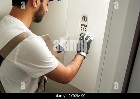 Professional male handyman in uniform is checking gas boiler working at home  Stock Photo