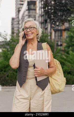 A Cheerful Senior Woman with a Smartphone Enjoys Her Time in an Urban City Setting Stock Photo