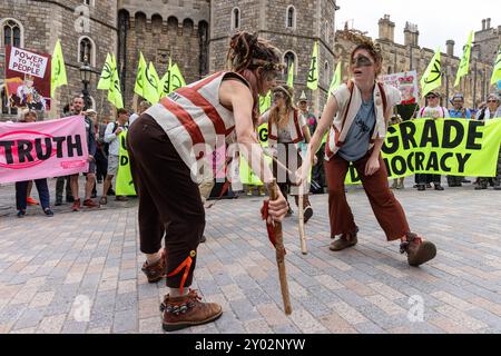 Windsor, UK. 31st August, 2024. Morris dancers perform outside Windsor Castle on the second of three days of Upgrade Democracy activities by Extinction Rebellion climate activists. Extinction Rebellion's Upgrade Democracy campaign is intended to highlight the manner in which profits are safeguarded for oil and gas companies in the UK and to call on the UK government to create and be led by a Citizens’ Assembly on Climate and Ecological Justice. Credit: Mark Kerrison/Alamy Live News Stock Photo