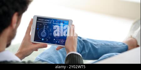 Young man holding tablet computer with smart home security system on screen Stock Photo