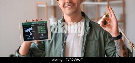 Young man holding tablet computer with smart home security system on screen Stock Photo