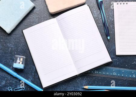 Notebooks with different stationery on grunge dark blue background Stock Photo