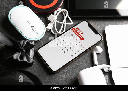 Mobile phone with calendar for November 2023, gift box and different devices on dark background. Black Friday concept Stock Photo