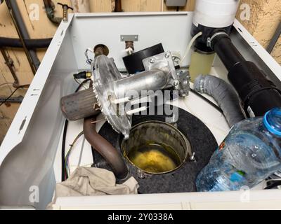 Inspecting and repairing a gas boiler in a garage, focusing on the open gas burning chamber and checking the water pump to ensure proper operation Stock Photo