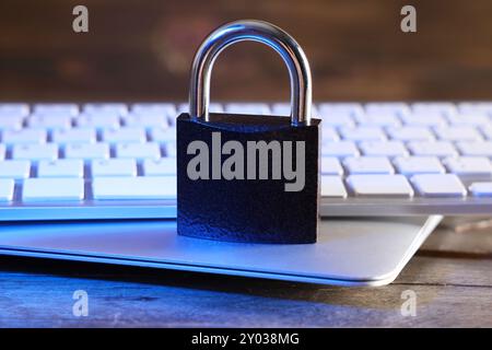 Padlock with laptop and computer keyboard on table, closeup. Cyber security concept Stock Photo
