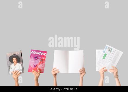 Female hands with different magazines and newspapers on grey background Stock Photo