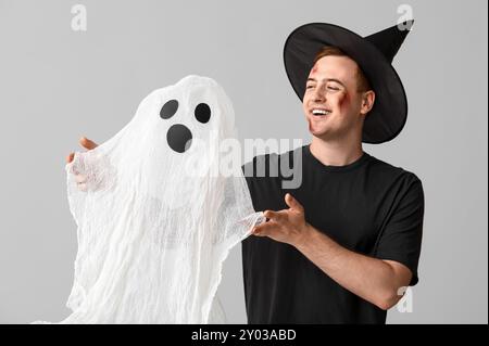 Young man dressed for Halloween as wizard with ghost on light background Stock Photo