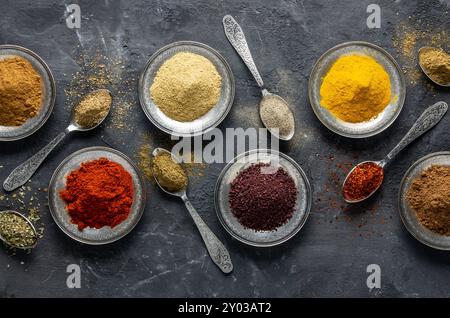 Assortment of natural spices on a vintage silver spoons or dishes on dark rustic stone background, Healthy spice concept Stock Photo