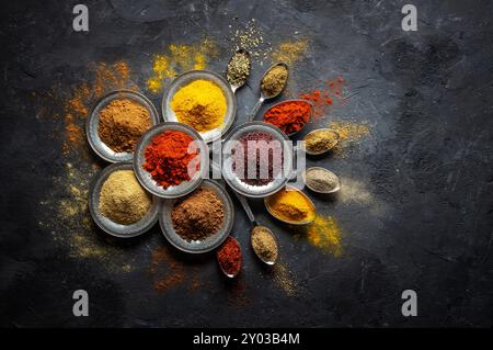Assortment of natural spices on a vintage silver spoons or dishes on dark rustic stone background, Healthy spice concept Stock Photo