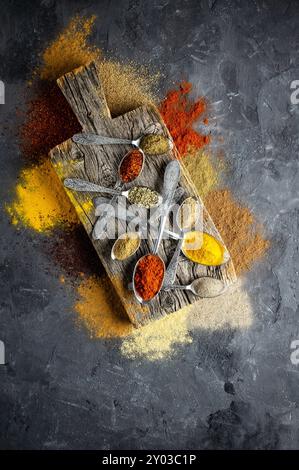 Assortment of natural spices on a vintage silver spoons or dishes on dark rustic stone background, Healthy spice concept Stock Photo