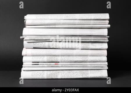 Stack of newspapers in different languages on black background Stock Photo