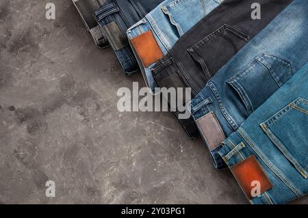 Stack of various denim jeans, trousers on stone rustic background, fashion design Stock Photo