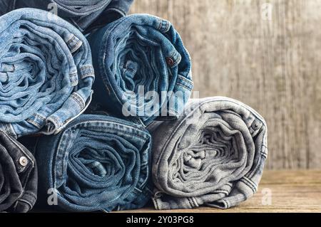 Stack of various denim jeans, trousers on stone rustic background, fashion design Stock Photo