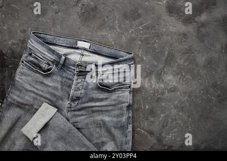 Single grey denim jean, trouser on stone rustic background, fashion design Stock Photo