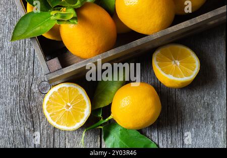 Fresh ripe yellow lemon fruits with leaves on wooden background Stock Photo