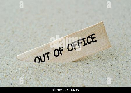 Out Of Office text on wooden stick with beach sand background. Off work concept. Stock Photo