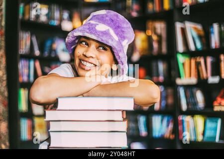 Thoughtful happy young woman leaning on pile of books in bookstore Stock Photo