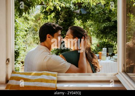 Romantic young couple kissing each other seen through window Stock Photo