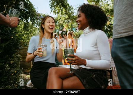 Cheerful female friends talking with each other while enjoying drinks at dinner party Stock Photo