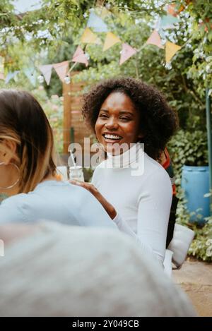 Smiling young woman with curly hair enjoying at dinner party Stock Photo