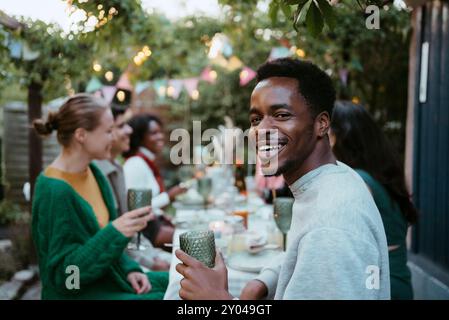 Side view portrait of smiling young man having fun with friends at party in back yard Stock Photo