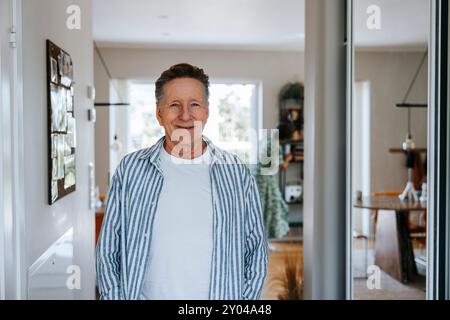 Portrait of smiling senior man in striped shirt at home Stock Photo