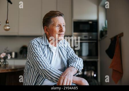 Thoughtful retired senior man in striped shirt at home Stock Photo