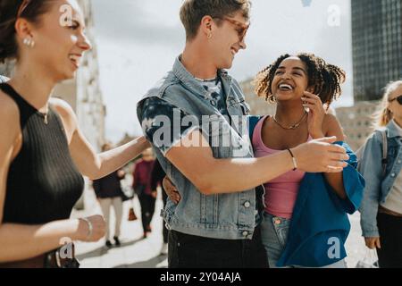 Happy young man having fun while walking with female friends at street Stock Photo