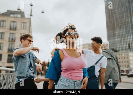 Happy fashionable young curly hair woman in sunglasses enjoying with male and female friends at street Stock Photo