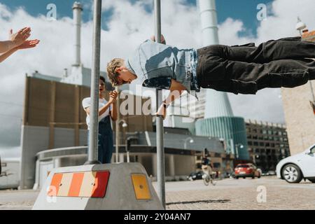 Athletic young man doing flag figure on pole at street Stock Photo